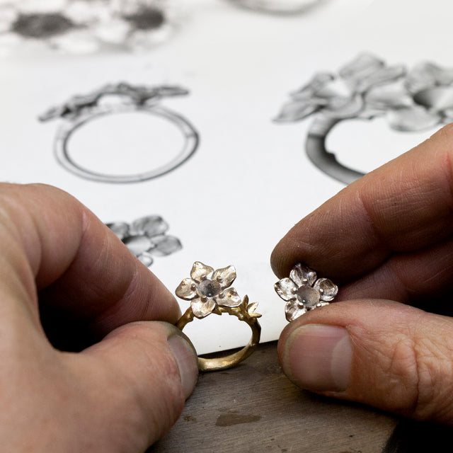 A bespoke flower ring next to its actual hand drawings.